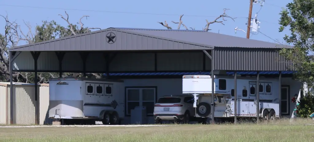 Metal barn and trailer shelter with a Texas star in the gable under a dark metal roof, roofed by Excell Roofing